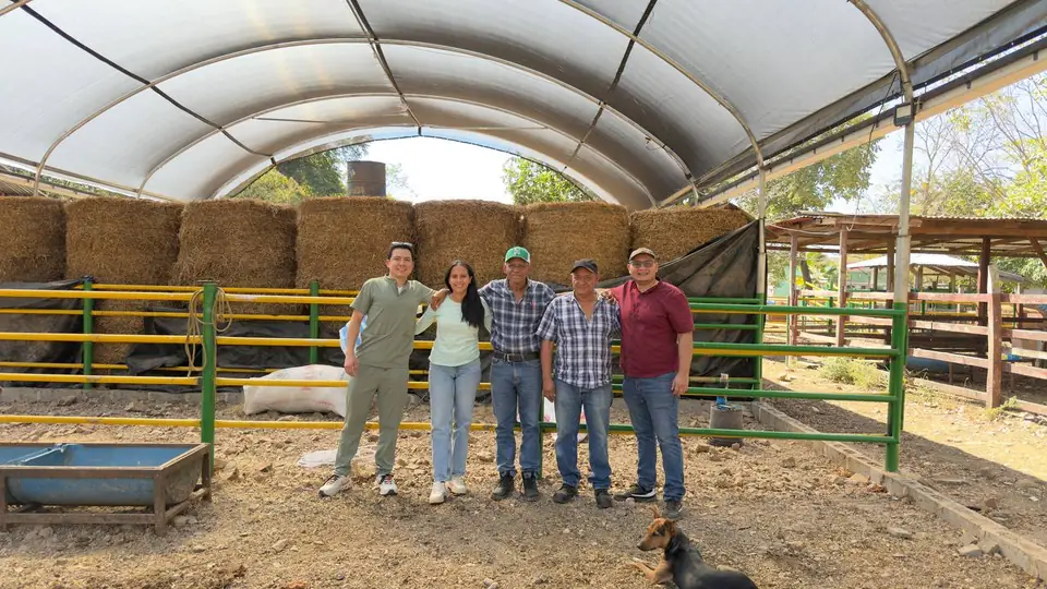 Cinco personas en un corral techado de la finca, con un perro al frente.